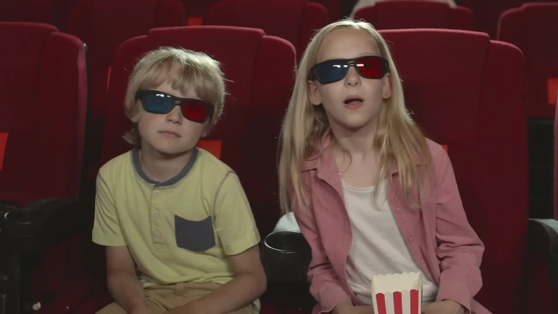 Zwei Kinder mit 3D-Brillen im Kinosessel