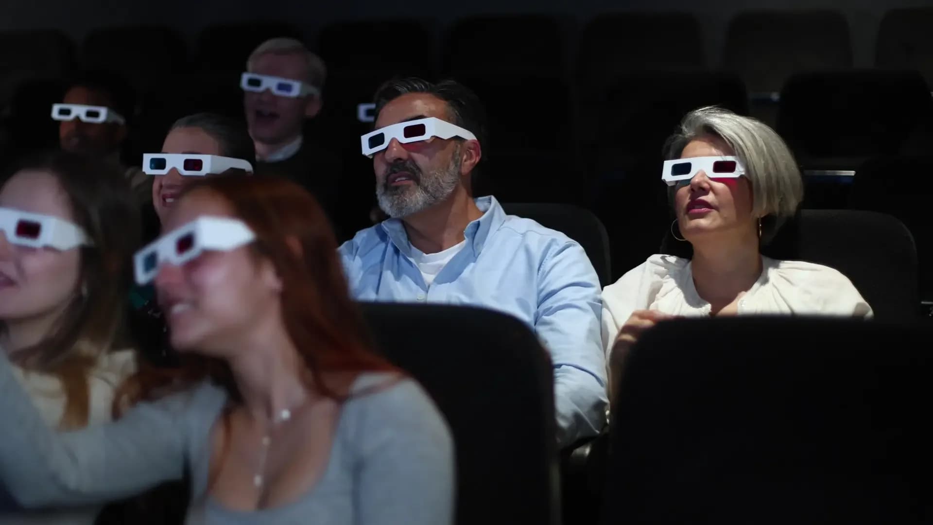 Zuschauer mit 3D-Brillen greifen staunend in die Luft